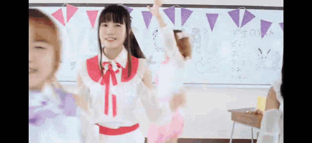 a group of girls are dancing in front of a whiteboard with chinese writing on it