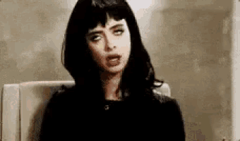 a woman is sitting in a chair with her eyes closed and making a funny face .