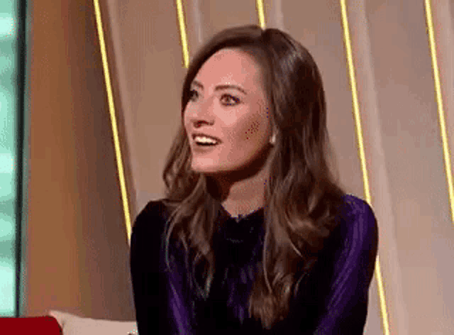 a woman is sitting on a couch and smiling .