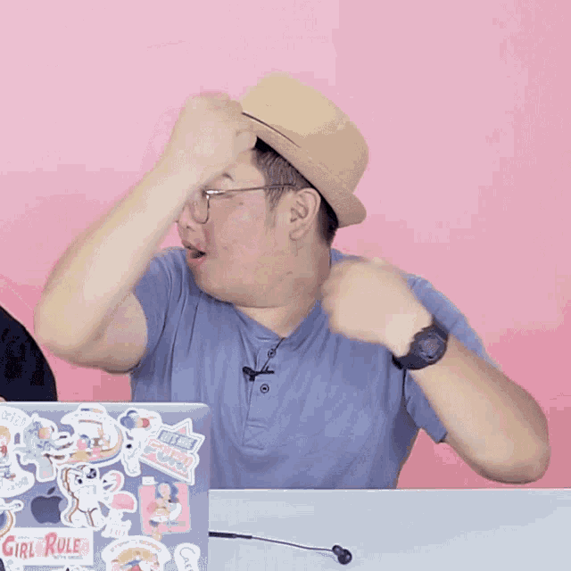 a man wearing a hat is sitting in front of a laptop with stickers on it including one that says girl rule