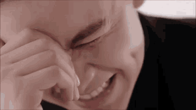 a close up of a man covering his face with his hand while laughing .