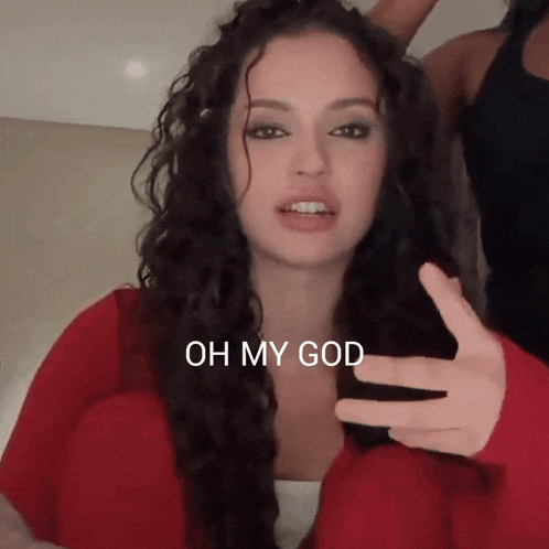 a woman with long curly hair says oh my god with her hand