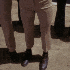 a person wearing khaki pants and black shoes is standing next to another person