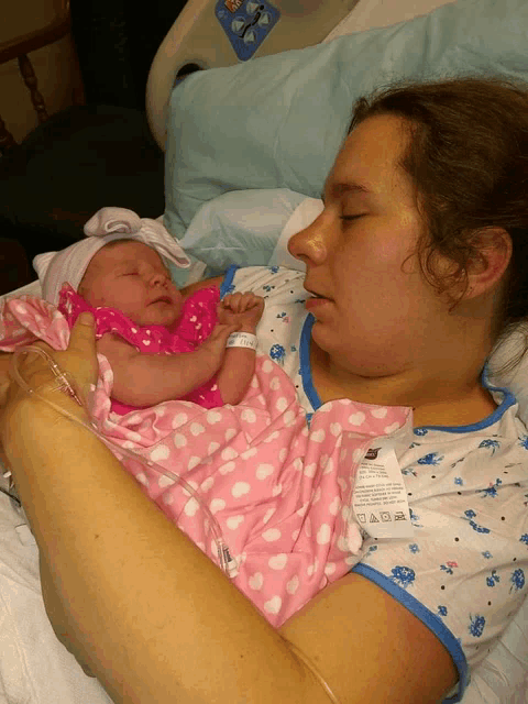 a woman in a hospital bed holds a newborn baby with a tag on her arm that says ' a ' on it