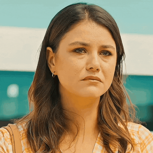 a woman with a sad look on her face is wearing hoop earrings