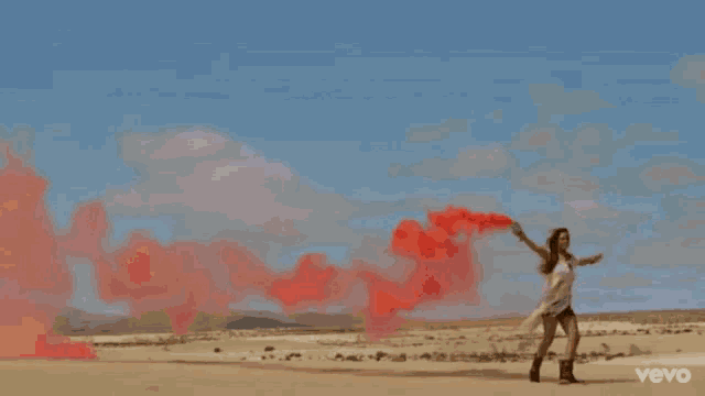 a woman with her arms outstretched is blowing red smoke into the air .