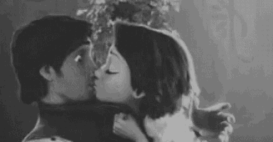 a black and white photo of a man and woman kissing each other .