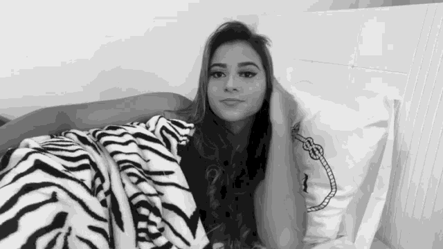 a woman is laying on a bed with a zebra print blanket .