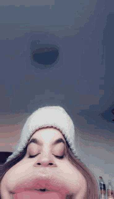 a girl wearing a white hat is making a funny face with her eyes closed