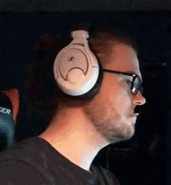 a man wearing headphones and glasses is sitting in a chair in a dark room .
