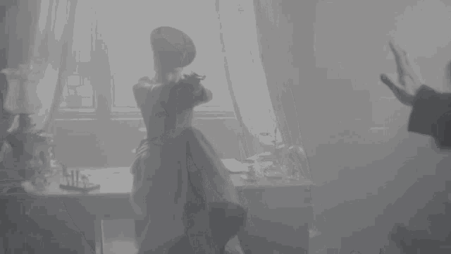 a woman in a dress is sitting at a table in a room .