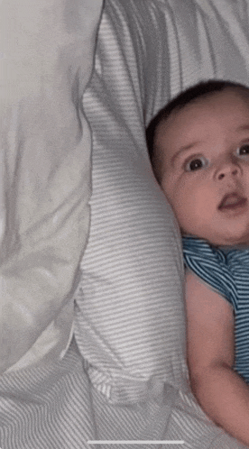 a baby is laying on a bed with a white pillow