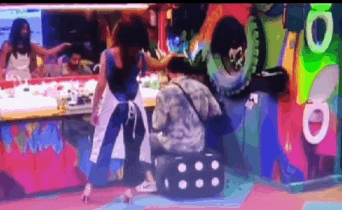 a woman standing next to a man kneeling down in front of a colorful wall with the number 10 on it .