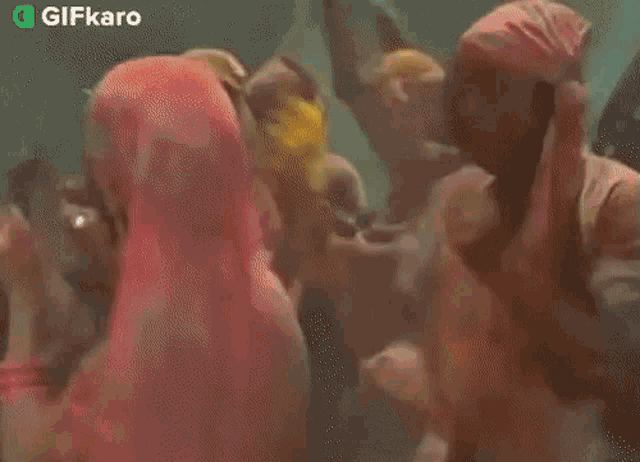 a group of people are dancing in a room with colored powder coming out of them .