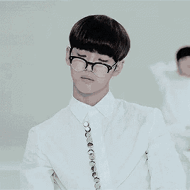 a young man wearing glasses and a white shirt and tie is making a funny face .