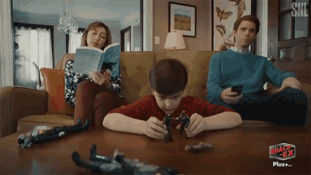 a family sitting on a couch playing with toys and a sign that says roach tea plus