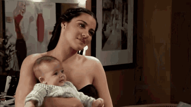 a woman is holding a baby in her arms and smiling