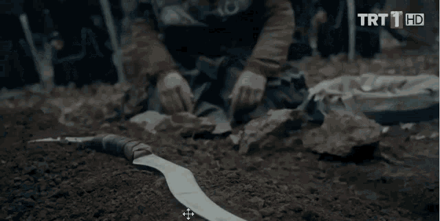 a group of men are standing around a man covered in dirt and the words trt 1 hd are on the screen .
