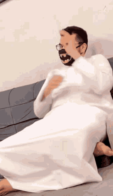 a man wearing a white robe and a batman mask sits on the floor