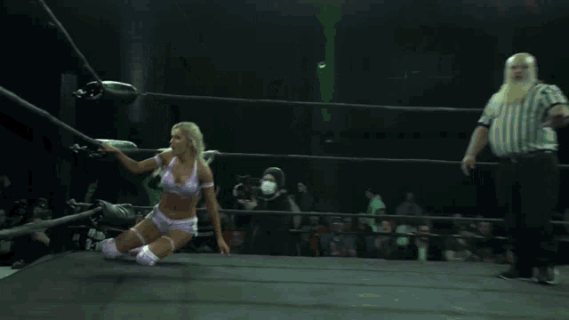 a woman in a wrestling ring with a referee behind her