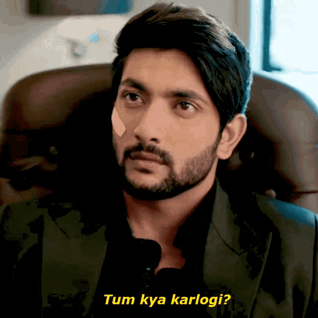 a man with a bandage on his face is sitting in a chair and says tum kya karlogi