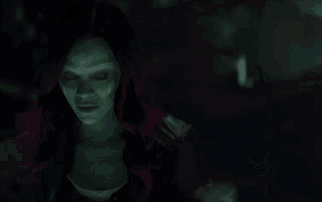 a woman with green hair and red eyes is looking down