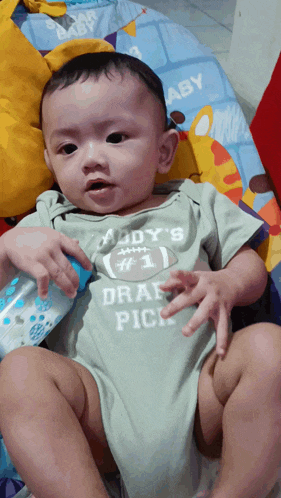 a baby wearing a daddy 's # 1 draft pick onesie
