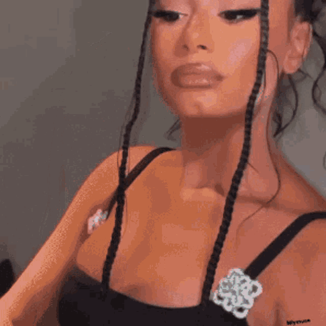 a close up of a woman 's face with braids and earrings .
