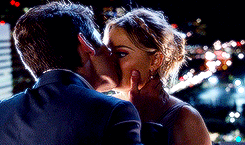 a man and woman are kissing in front of a city skyline at night
