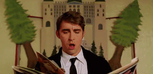a man in a suit and tie is reading a magazine while sitting in front of a castle .