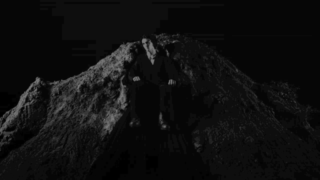 a man in a suit is sitting on top of a pile of dirt