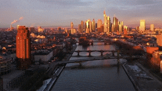 an aerial view of a city skyline at sunset with a bridge in the foreground