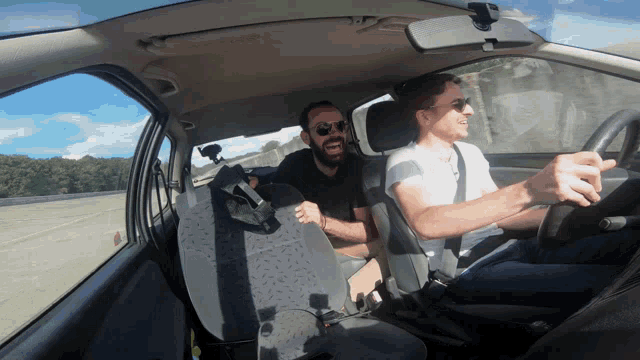 a man driving a car with another man sitting in the back seat laughing