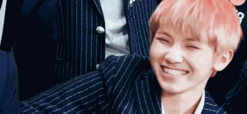 a close up of a person with pink hair smiling .