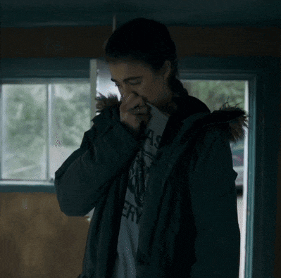 a woman covering her nose with her hand while wearing a jacket that says easy