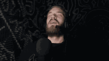 a man with a beard wearing headphones and a microphone with his eyes closed .