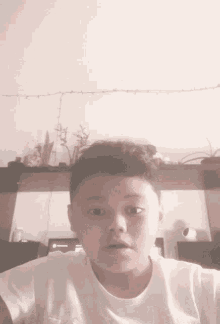 a young boy in a white shirt is making a funny face while looking at the camera