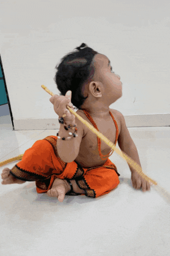a baby in an orange outfit is playing with a stick