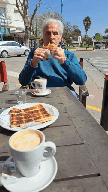 a man sits at a table with a cup of coffee and a plate of food