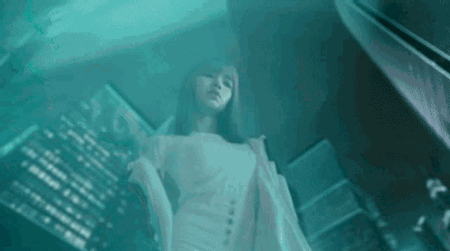 a woman in a white dress is standing in front of a tall building in a dark room .