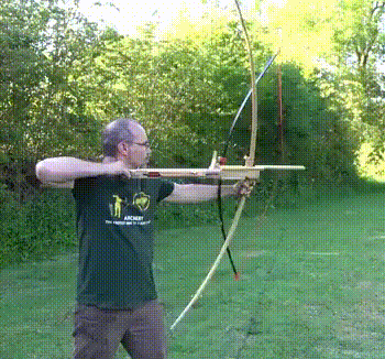 a man in a green shirt that says archery is holding a bow and arrow