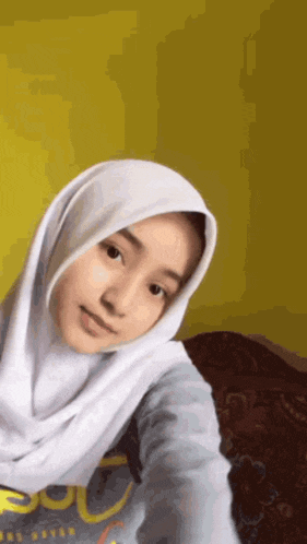 a girl wearing a white hijab and a sweatshirt that says superdry