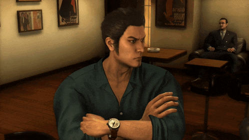 a man with a watch on his wrist is sitting in a room with a poster on the wall that says arnold schwarzenegger