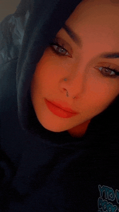 a close up of a woman 's face with a nose ring and a hoodie that says ytl hop
