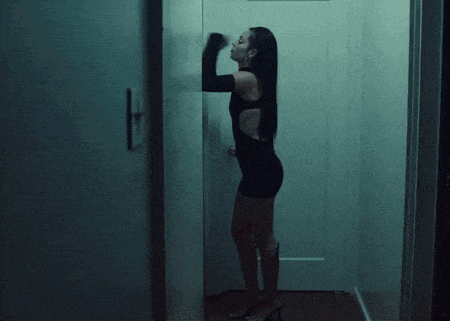 a woman in a black dress is leaning against a wall