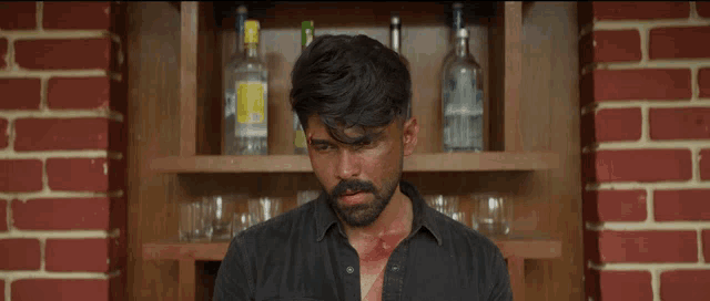 a man standing in front of a shelf with bottles of vodka