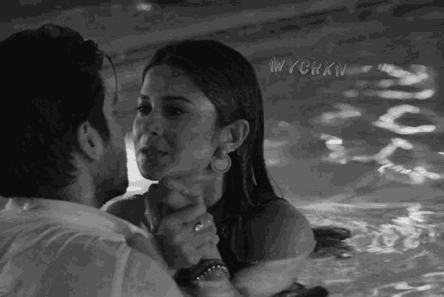 a black and white photo of a man and woman in a pool