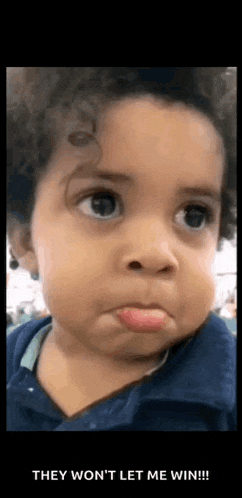 a baby with curly hair is making a funny face with his tongue sticking out .