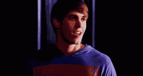 a young man wearing a purple and red striped shirt is smiling .