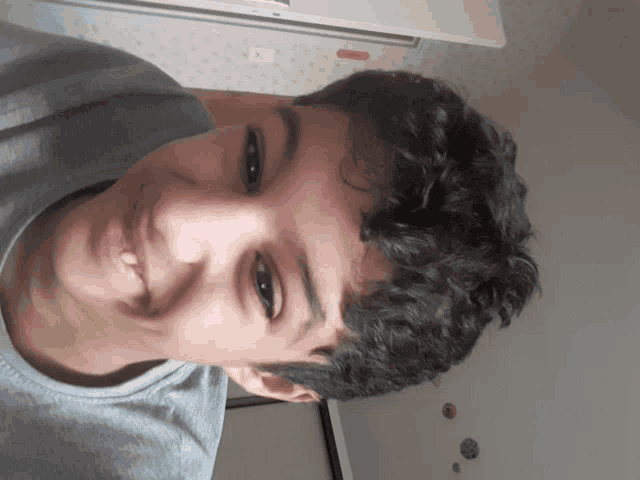 a young boy with curly hair is smiling and looking at the camera